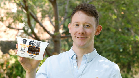 Hugh Maguire Junior holding a pack of The Smokin' Butcher black pudding