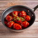 Black skillet with Hugh Maguire Butchers beef meatballs in a red sauce on a wooden surface